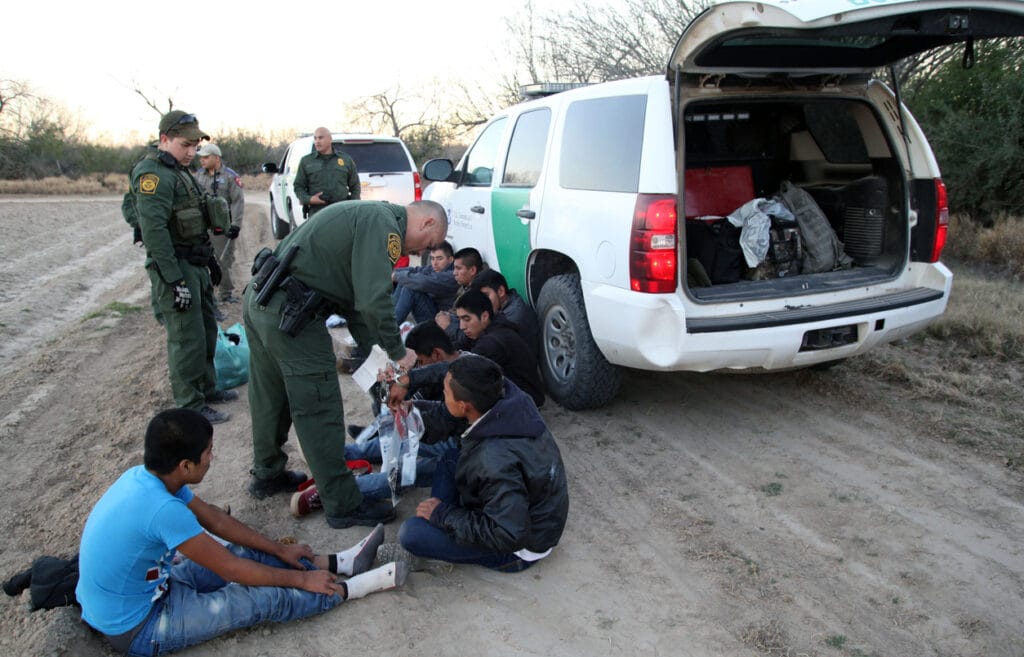 Fronton, Texas, USA - February 9, 2016: A Border Patrol agent removes handcuffs from a young Central American being taken into custody for illegally entering the United States by crossing the Rio Grande River in deep south Texas.