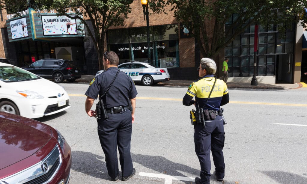 Asheville, NC, Two police officers wait to cross Haywood Avenue.