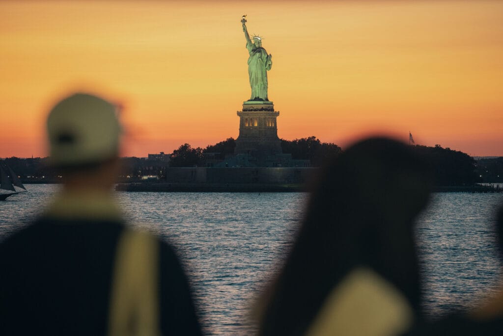 Passengers on the Staten Island Ferry watch as the Statue of Liberty passes in the background. 