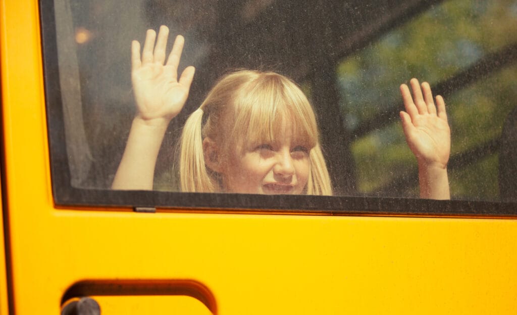 Portrait of a young girl looking out the back window of a school bus.
