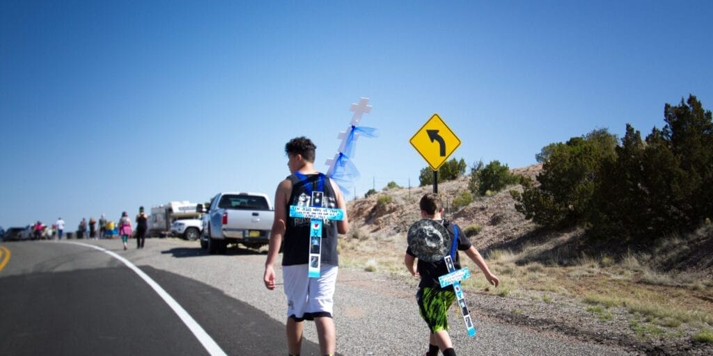 Chimayo, NM, USA - April 14, 2017: Young pilgrims participate in the Good Friday pilgrimage walk to the Santuario de Chimayo in northern NM, about 30 miles north of Santa Fe. Tens of thousands of pilgrims walk to the Chimayo chapel every year to seek blessings, renew their faith, and pray.