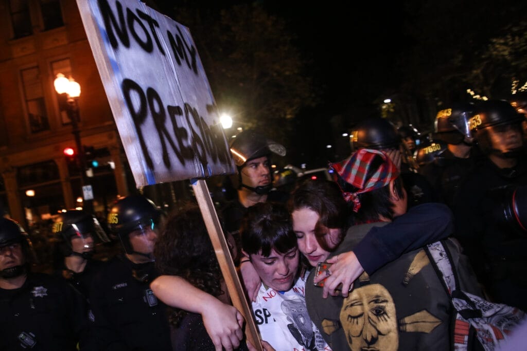 Oakland, California, USA - November 9, 2016: Protestors hug each other as police officers move in on a riot against the President-elect Donald Trump.