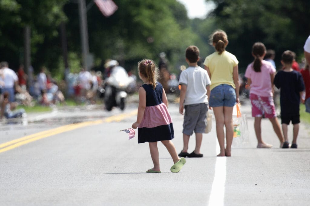 Penfield, New York, USA - July 4th, 2008: Children waiting expectantly for the Penfield town Independence Day parade to start are finally rewarded as the lead Monroe County Sheriff Department motorcycle comes into view.