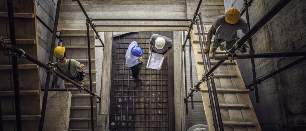 Construction workers and architects at a construction site viewed from above.
